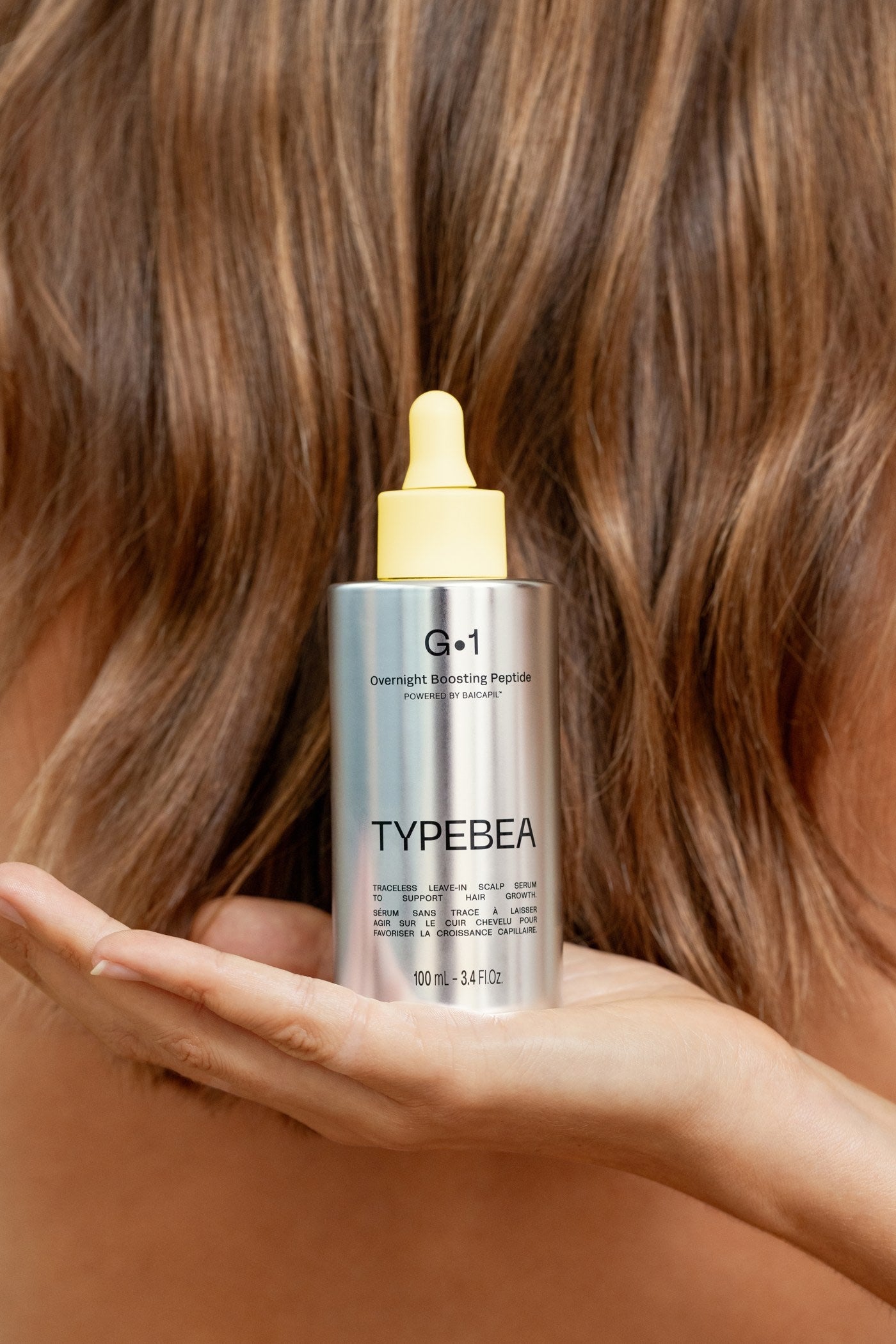 Model holding G·1 against her hair